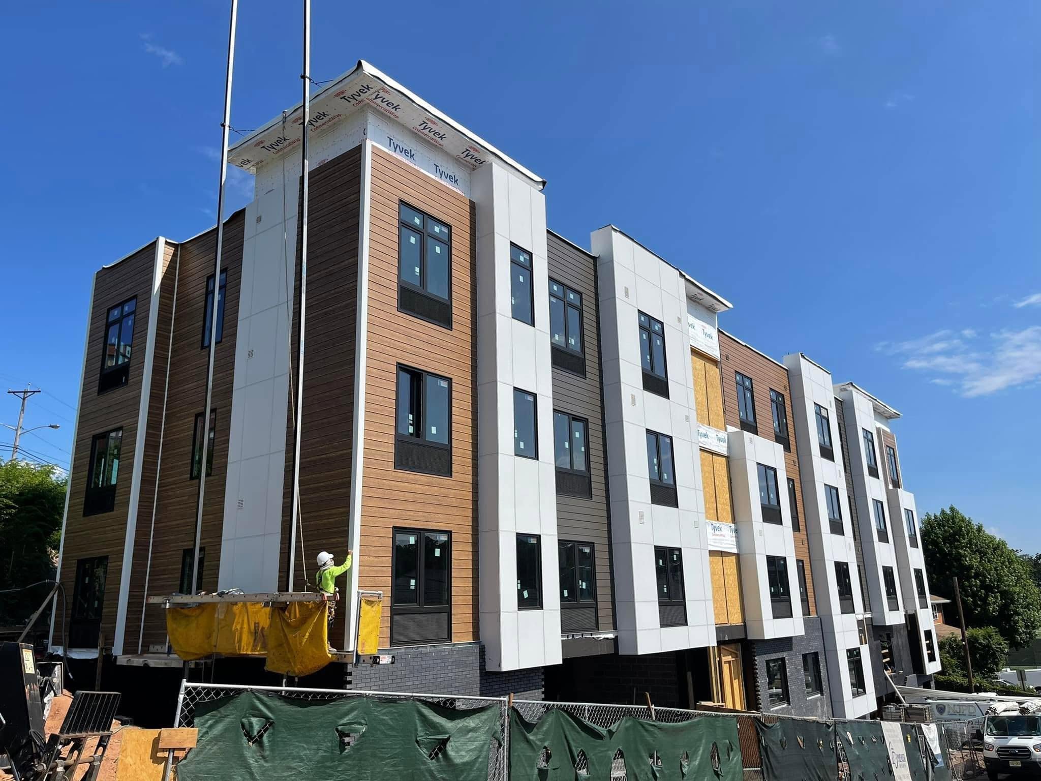 Multi-story building with brown horizontal siding, white exterior panels and dark accents, from Empire Siding's project photo collection